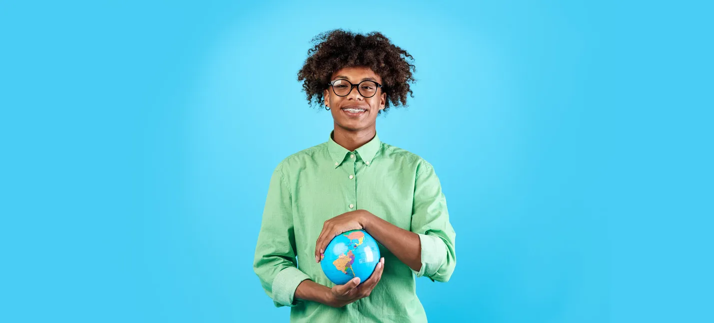 Photo d’un adolescent qui tient un globe terrestre entre ses mains.